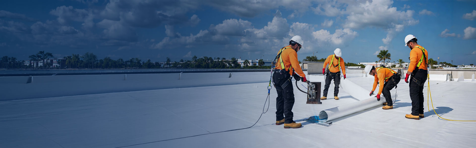 TPO roofing installation crew rolling out membrane on a Miami commercial roof