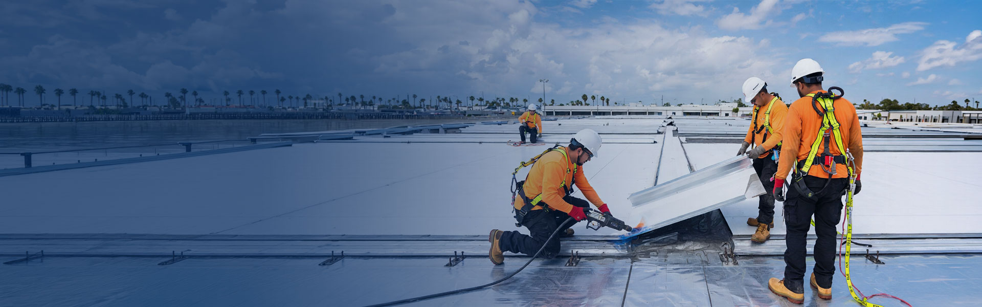 Warehouse roofing crew installing TPO membrane on a large Miami-Dade industrial building
