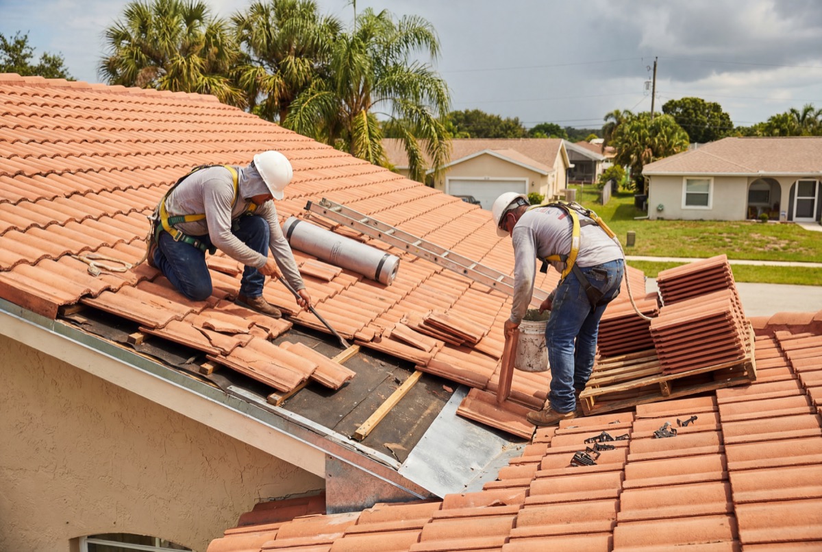 Roofers installing clay tiles on house roof