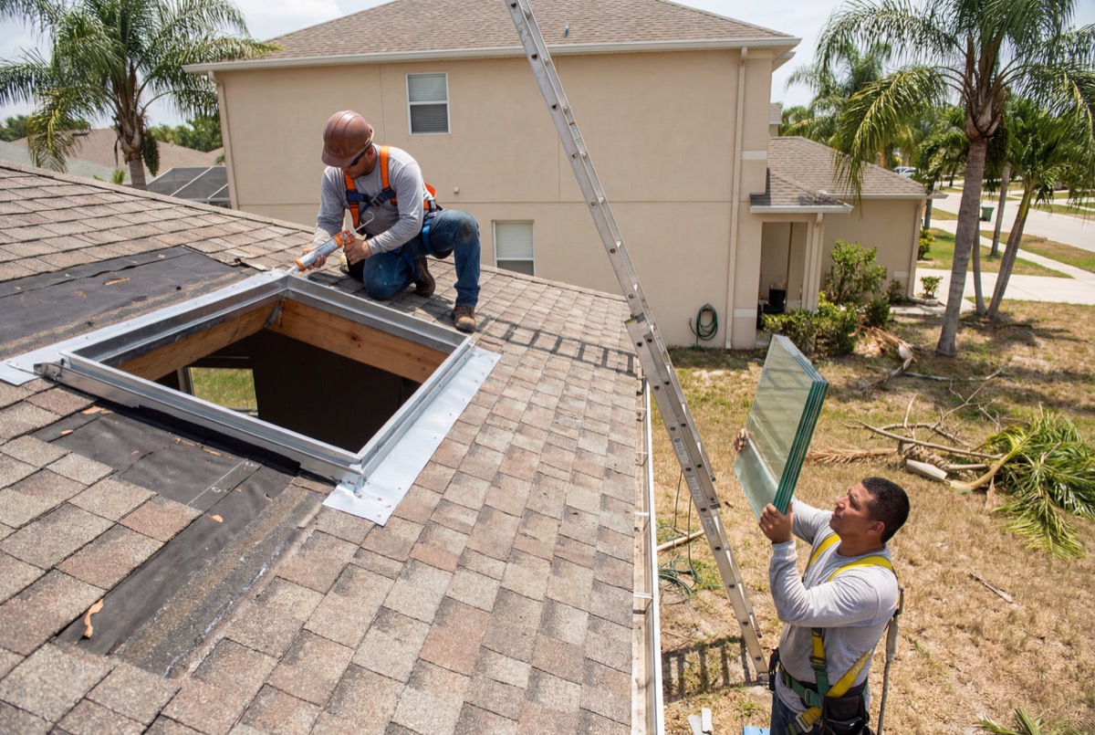 Roofer installing skylight on house roof