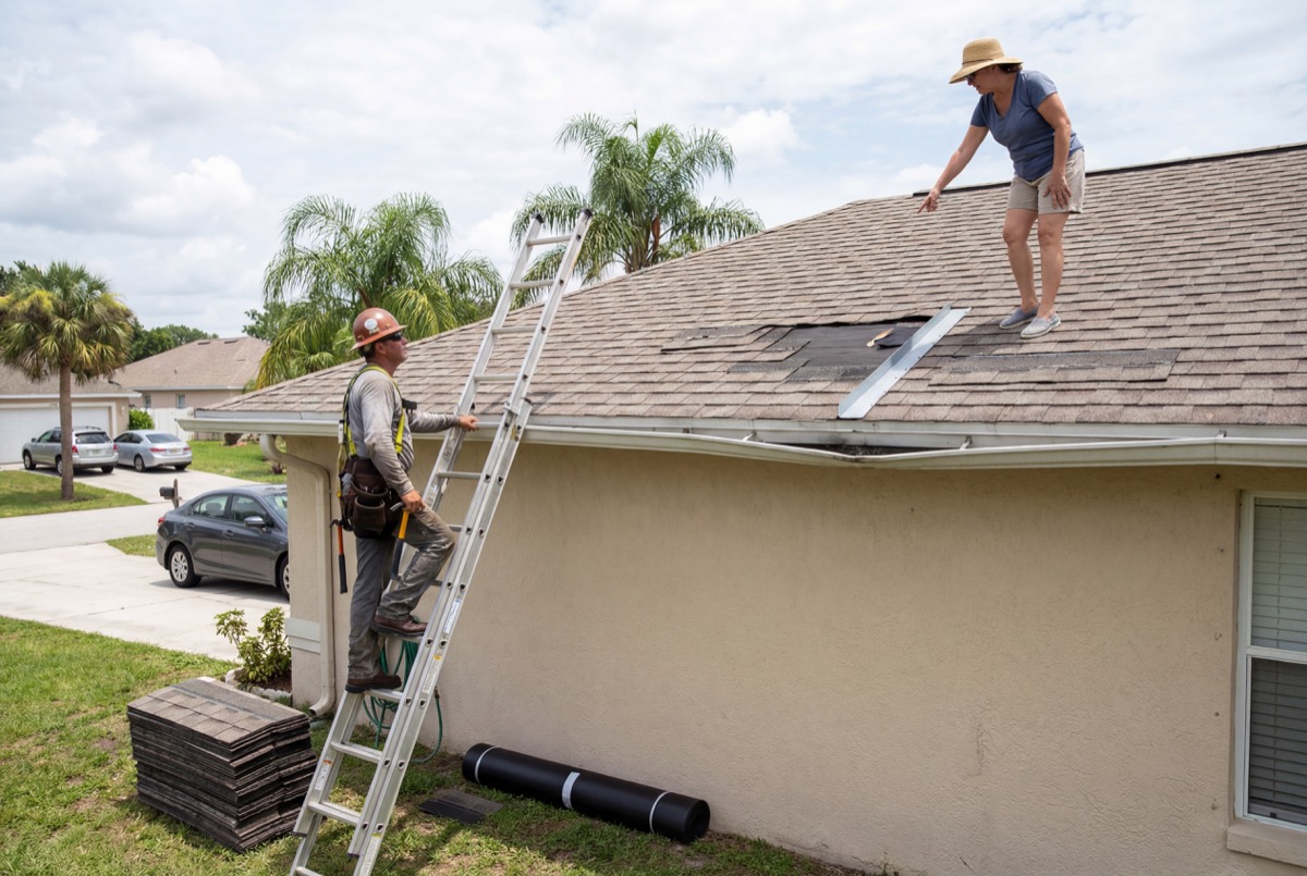Workers installing shingles on house roof