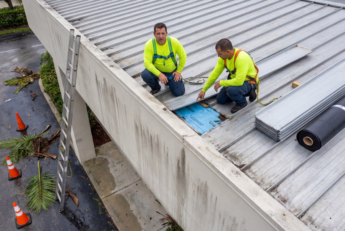 Roofers repairing metal roof panels outdoors