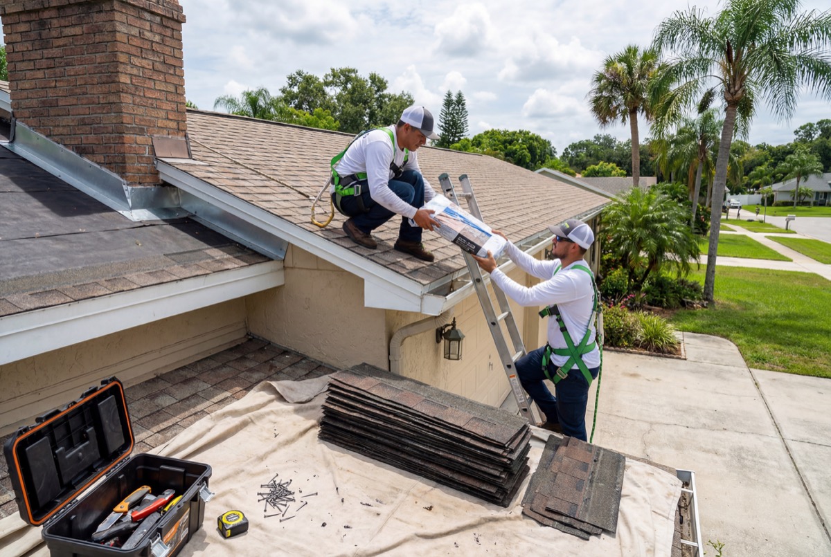 Roofers installing solar panels on house roof