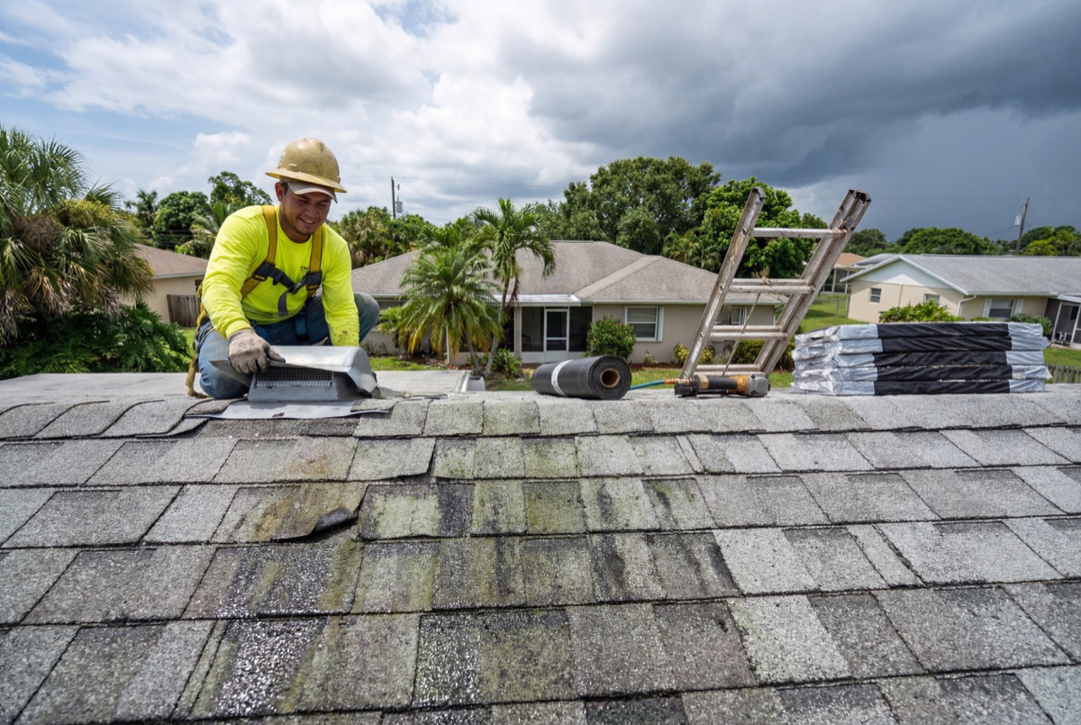 Roofer installing shingles on house roof