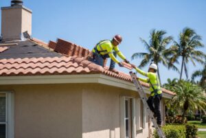 Roofers installing tiles on house roof outdoors