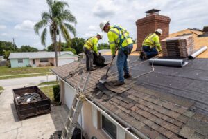 Roofers installing shingles on house roof